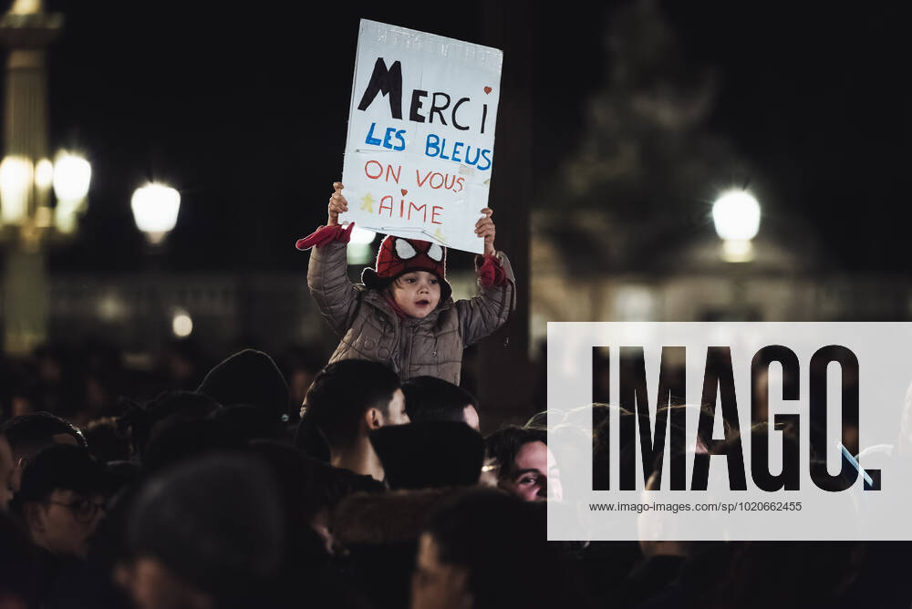 French Football Team Fans Greet The Players On The Place De La Concorde In Paris A child supporter of the French football team holds up a sign reading Merci les bleus (Thank you France) as a crowd gathers on the Place de la Concorde to welcome the players on the balcony of the Crillon hotel after their return from Qatar after their defeat by Argentina in the World Cup final in Paris December 19, 2022. Paris France