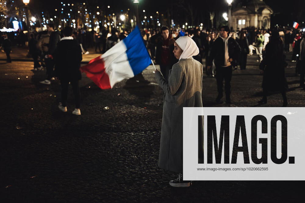 French Football Team Fans Greet The Players On The Place De La Concorde In Paris A fan of the France team wearing the veil waves a French flag in the middle of the crowd gathered in the Place de la Concorde to welcome the players present on the balcony of the Hotel de Crillon after their return from Qatar after their defeat against Argentina in the final of the World Cup, in Paris, on December 19, 2022. Paris France