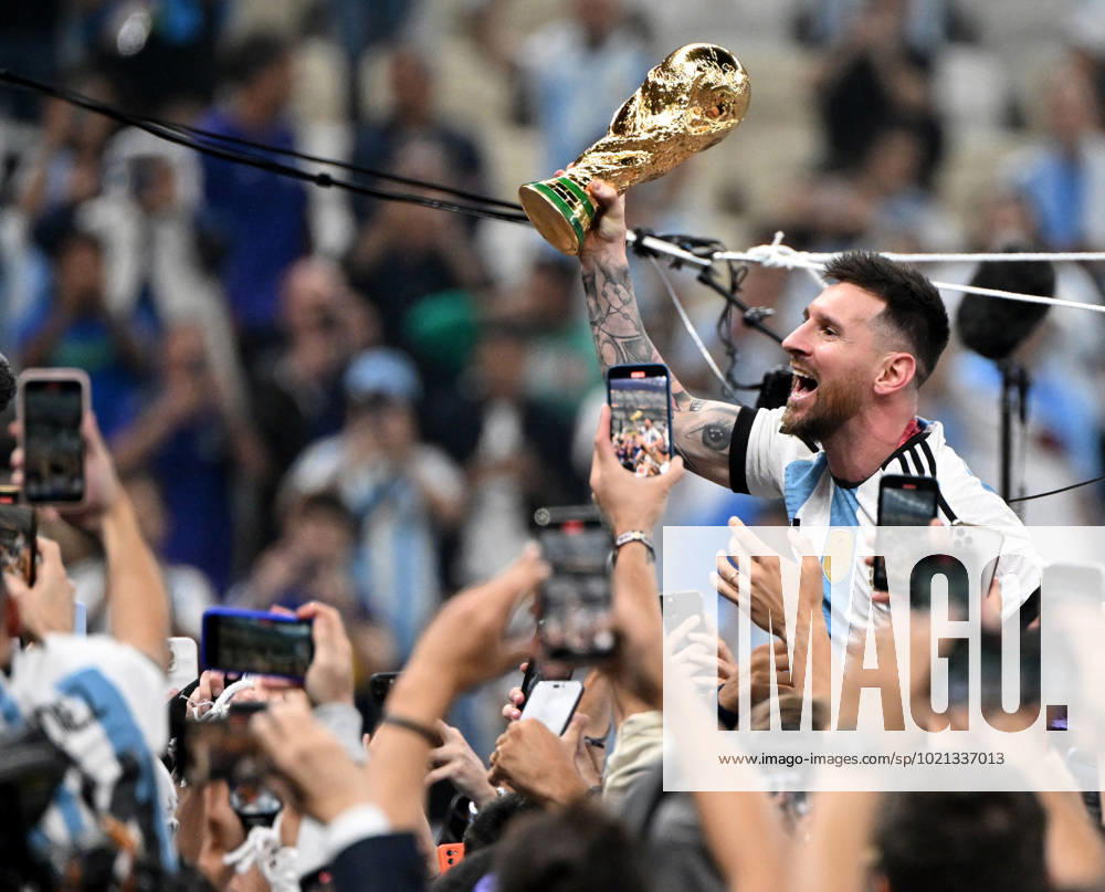 Football, men, season 2022 23, World Cup in Qatar, final, Argentina France 2 2, 3 3 n V, 4 2 i E at Lusail Iconic Stadium in Lusail, Lionel Messi Argentina with trophy, he is carried on shoulders long after the end of the game in the area behind the goal, he is photographed and filmed by fans with cell phones, cheering after the final whistle, 18 12 2022,
