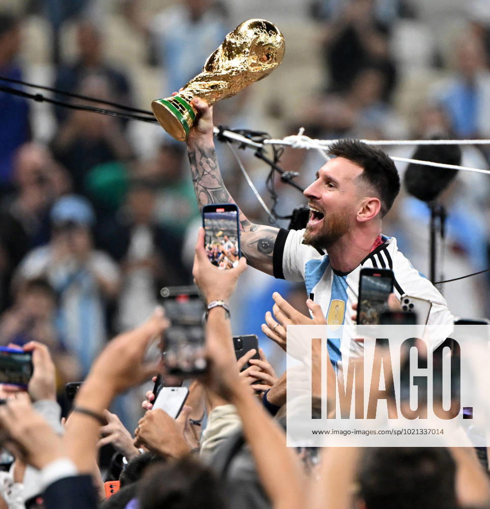 Football, men, season 2022 23, World Cup in Qatar, final, Argentina France 2 2, 3 3 n V, 4 2 i E at Lusail Iconic Stadium in Lusail, Lionel Messi Argentina with trophy, he is carried on shoulders long after the end of the game in the area behind the goal, he is photographed and filmed by fans with cell phones, cheering after the final whistle, 18 12 2022,