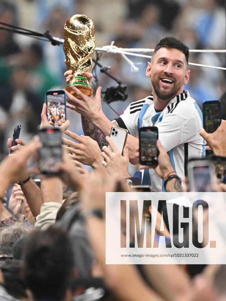 Football, men, season 2022 23, World Cup in Qatar, final, Argentina France 2 2, 3 3 n V, 4 2 i E at Lusail Iconic Stadium in Lusail, Lionel Messi Argentina with trophy, he is carried on shoulders long after the end of the game in the area behind the goal, he is photographed and filmed by fans with cell phones, cheering after the final whistle, 18 12 2022,