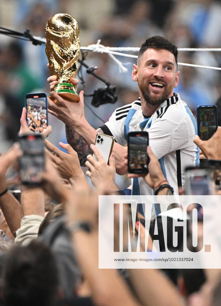 Football, men, season 2022 23, World Cup in Qatar, final, Argentina France 2 2, 3 3 n V, 4 2 i E at Lusail Iconic Stadium in Lusail, Lionel Messi Argentina with trophy, he is carried on shoulders long after the end of the game in the area behind the goal, he is photographed and filmed by fans with cell phones, cheering after the final whistle, 18 12 2022,