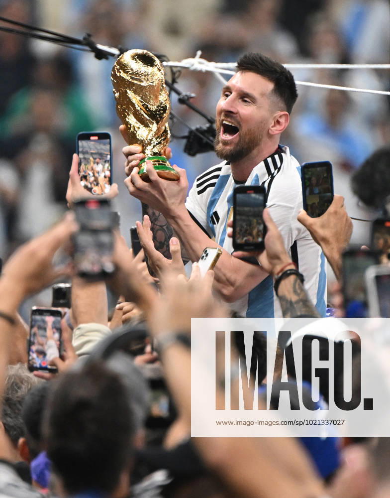 Football, men, season 2022 23, World Cup in Qatar, final, Argentina France 2 2, 3 3 n V, 4 2 i E at Lusail Iconic Stadium in Lusail, Lionel Messi Argentina with trophy, he is carried on shoulders long after the end of the game in the area behind the goal, he is photographed and filmed by fans with cell phones, cheering after the final whistle, 18 12 2022,