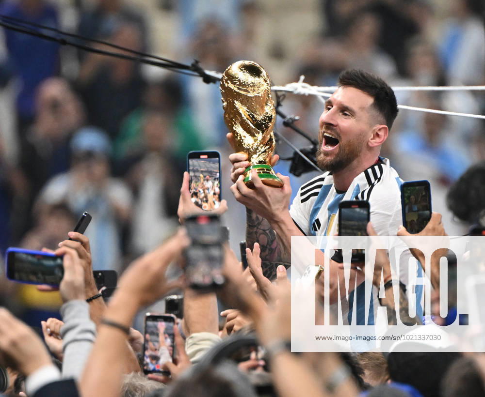 Football, men, season 2022 23, World Cup in Qatar, final, Argentina France 2 2, 3 3 n V, 4 2 i E at Lusail Iconic Stadium in Lusail, Lionel Messi Argentina with trophy, he is carried on shoulders long after the end of the game in the area behind the goal, he is photographed and filmed by fans with cell phones, cheering after the final whistle, 18 12 2022,