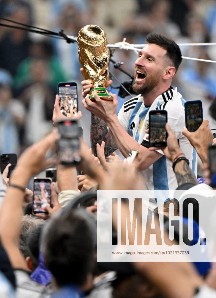 Football, men, season 2022 23, World Cup in Qatar, final, Argentina France 2 2, 3 3 n V, 4 2 i E at Lusail Iconic Stadium in Lusail, Lionel Messi Argentina with trophy, he is carried on shoulders long after the end of the game in the area behind the goal, he is photographed and filmed by fans with cell phones, cheering after the final whistle, 18 12 2022,