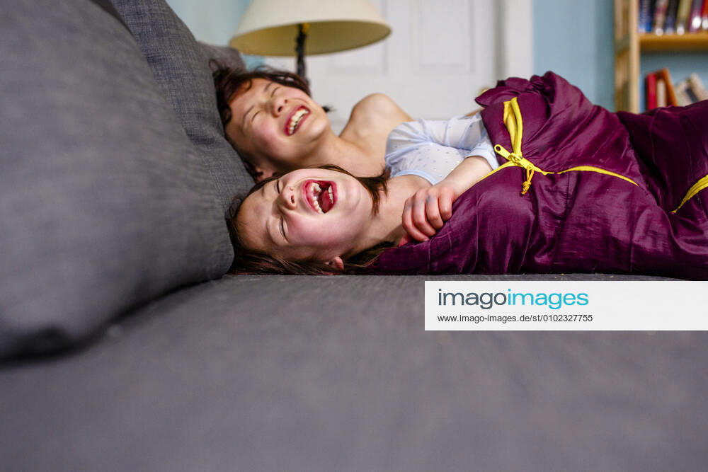 Two happy children lay on couch together laughing out loud with joy Columbus, OH, United States CR_RETI200701A-380927-01 ,model released, Symbolfoto