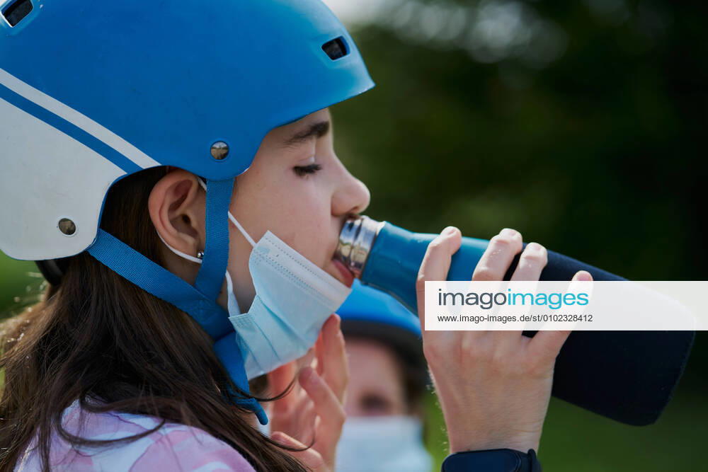 IMAGO Creative: 2022 Farbe des Jahres: Very Peri, Veilchenblau girl with the mask and the riding helmet drinks water from a bottle Pamplona, Navarre, Spain CR_SEBO200707B-408351-01 ,model released, Symbolfoto