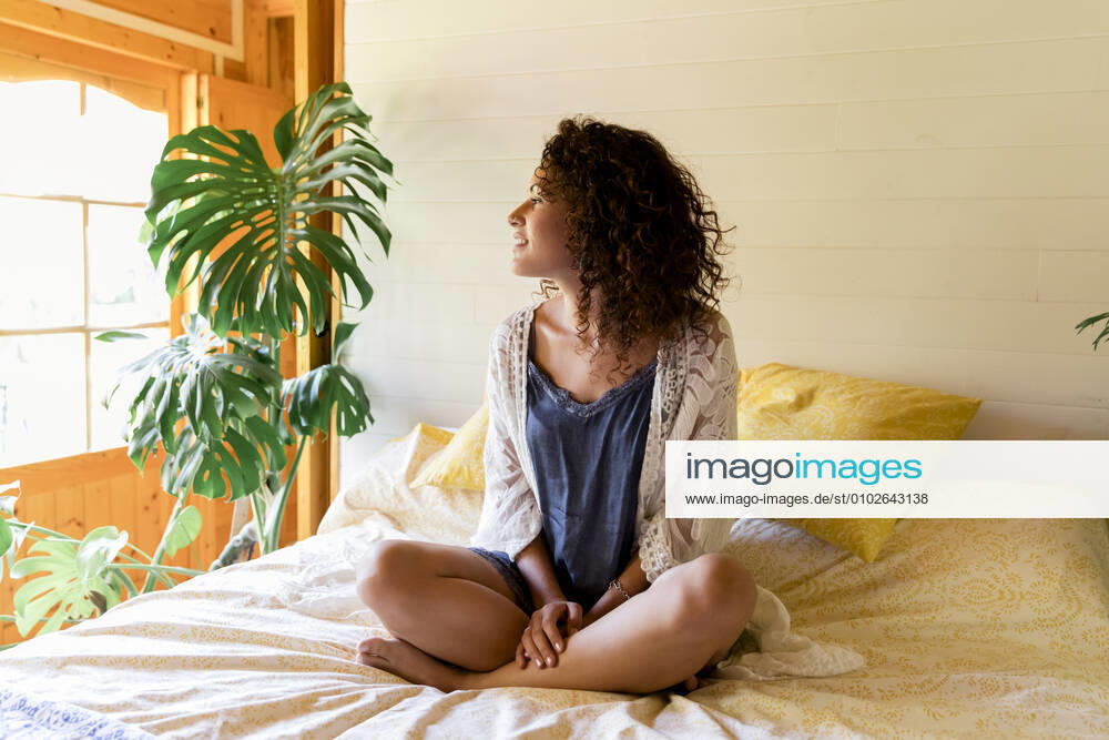 Relaxed young woman sitting on bed in log cabin model released Symbolfoto property released LVVF00119