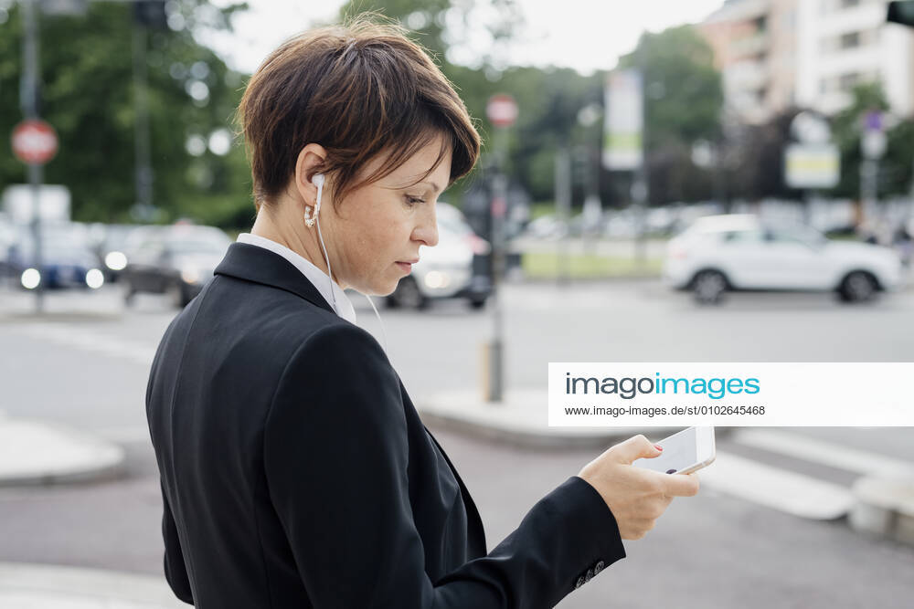 Close-up of female professional using smart phone while standing on street in city model released Symbolfoto MEUF01218