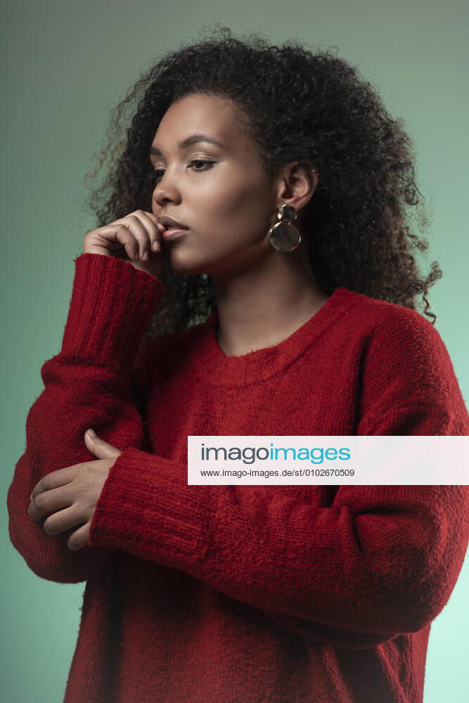 Thoughtful young woman with curly hair standing against blue background model released Symbolfoto SNF00316