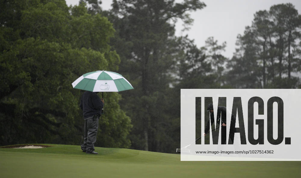 Grounds crew squeegee the 18th green at the conclusion of the rain delayed second round at the 87th Masters tournament at Augusta National Golf Club in Augusta, Georgia on Saturday, April 8, 2023. Brooks Kopek leads the tournament at 132, 12 under par. AUG20230408206 BOBxSTRONG