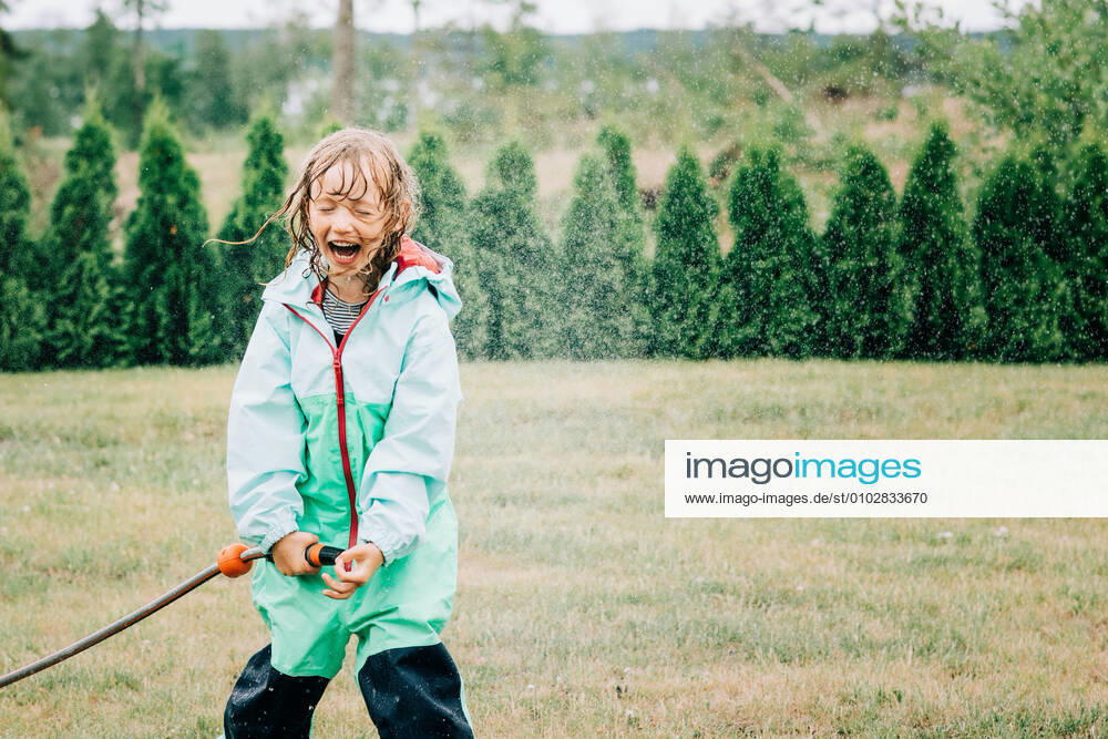 Girl laughing whilst playing with water in the yard at home Norrtälje, Stockholm County, Sweden CR_RABE200715-442567-01 ,model released, Symbolfoto