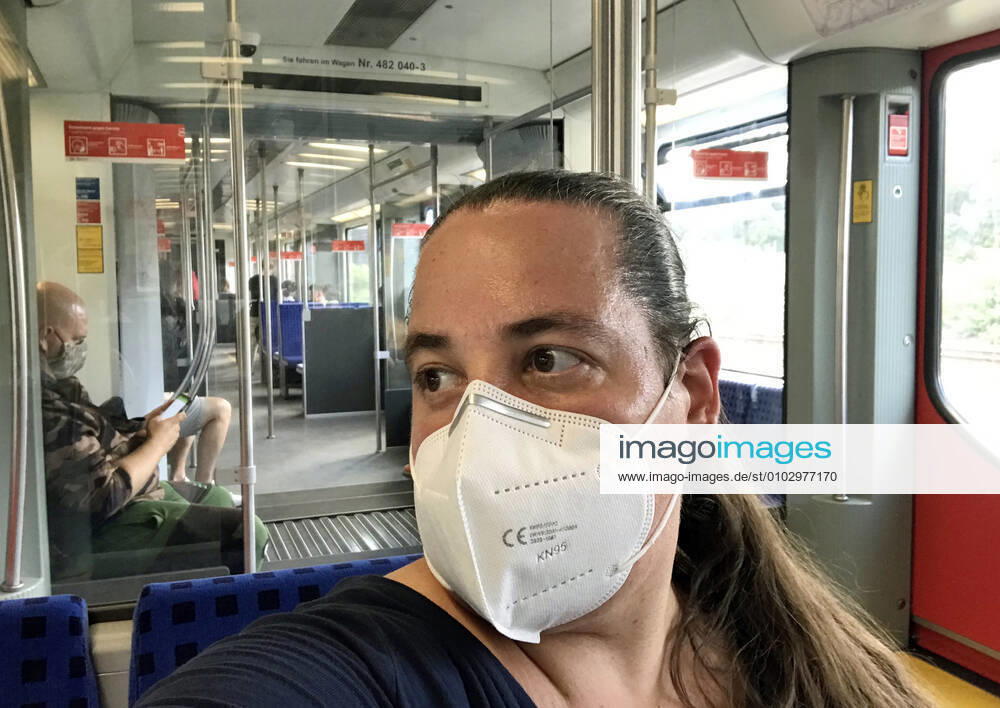 Berlin, GER - Frau in einer S-Bahn traegt in Zeiten der Coronapandemie eine Atemmaske. (40-50 Jahre, Abteil, Alltag, Atemmaske, Bahn, Berlin, Coronaepidemie, Coronainfektion, Coronakrise, Coronapandemie, Coronavirus, Coronavirus SARS-CoV-2, Covid 19, Covid-19, deutsch, Deutschland, Europa, europaeisch, Fenster, FFP2, FFP2-Maske, Frau, geschuetzt, Gesellschaft, innen, Innenaufnahme, Jahreszeit, Kaukasierin, kaukasisch, Maske, Maskengebot, Maskenpflicht, Mensch, Mund-Nase-Schutz, Mund-Nasen-Schutz, Mundschutz, Mundschutzgebot, Mundschutzpflicht, Nahverkehr, oeffentlicher Personennahverkehr, OEPNV, Person, Personennahverkehr, QF, Querformat, S-Bahn, Schutz, Schutzmaske, Sommer, verpflichtend, Verpflichtung, Waggon, Westeuropa, Wirt