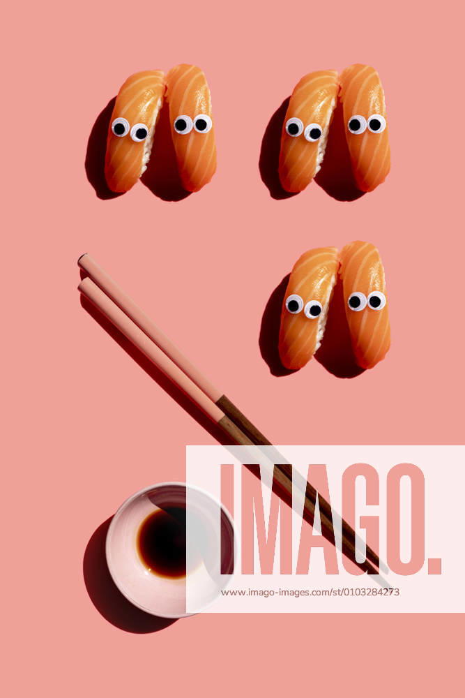 Studio shot of chopsticks, bowl of soy sauce and salmon nigirizushi pieces with googly eyes GEMF03928