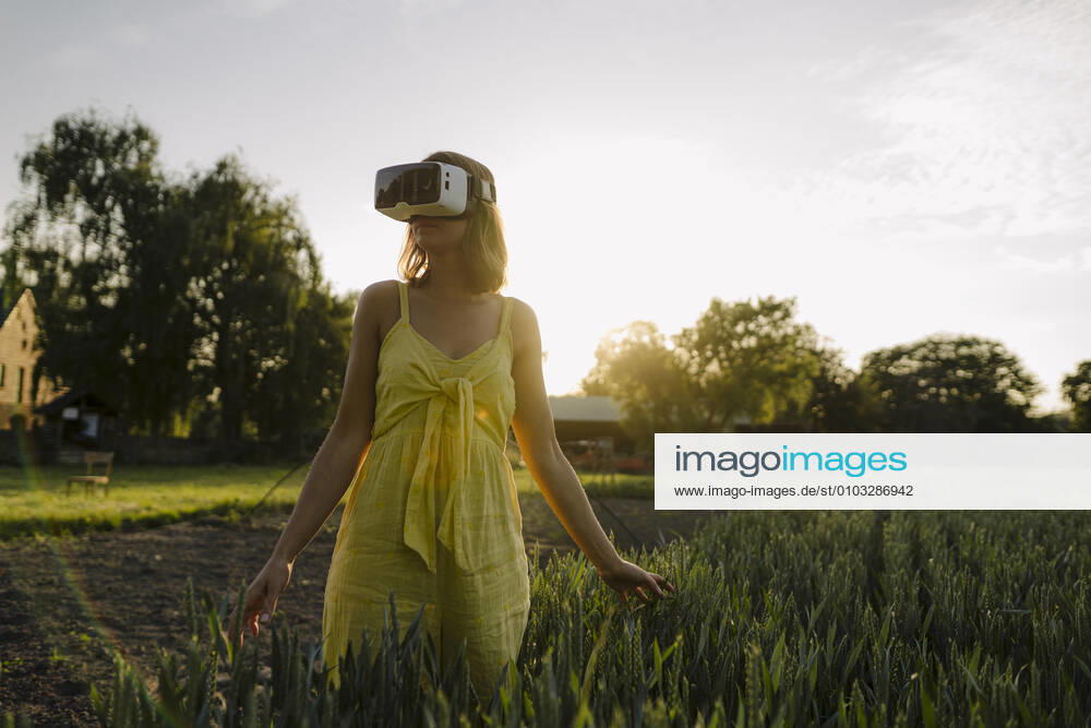 Young woman wearing VR goggles in a grain field in the countryside model released Symbolfoto property released GUSF04276