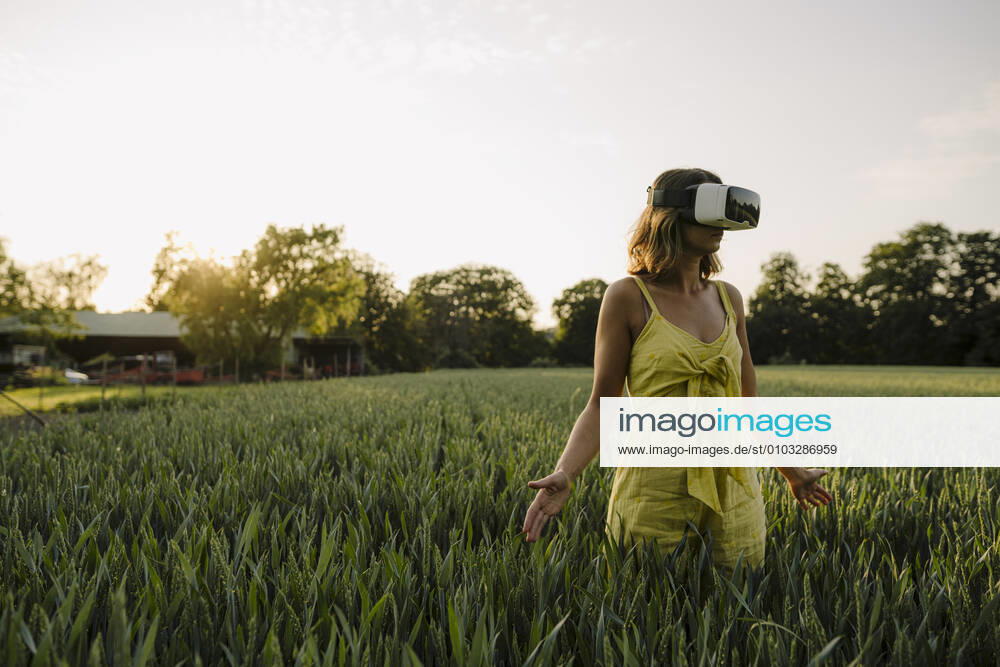 Young woman wearing VR goggles in a grain field in the countryside model released Symbolfoto property released GUSF04280