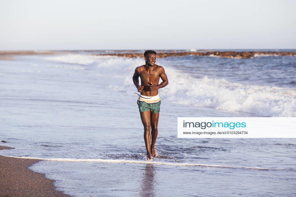 Shirtless African young man running at shore against clear sky model released Symbolfoto property released LJF01707