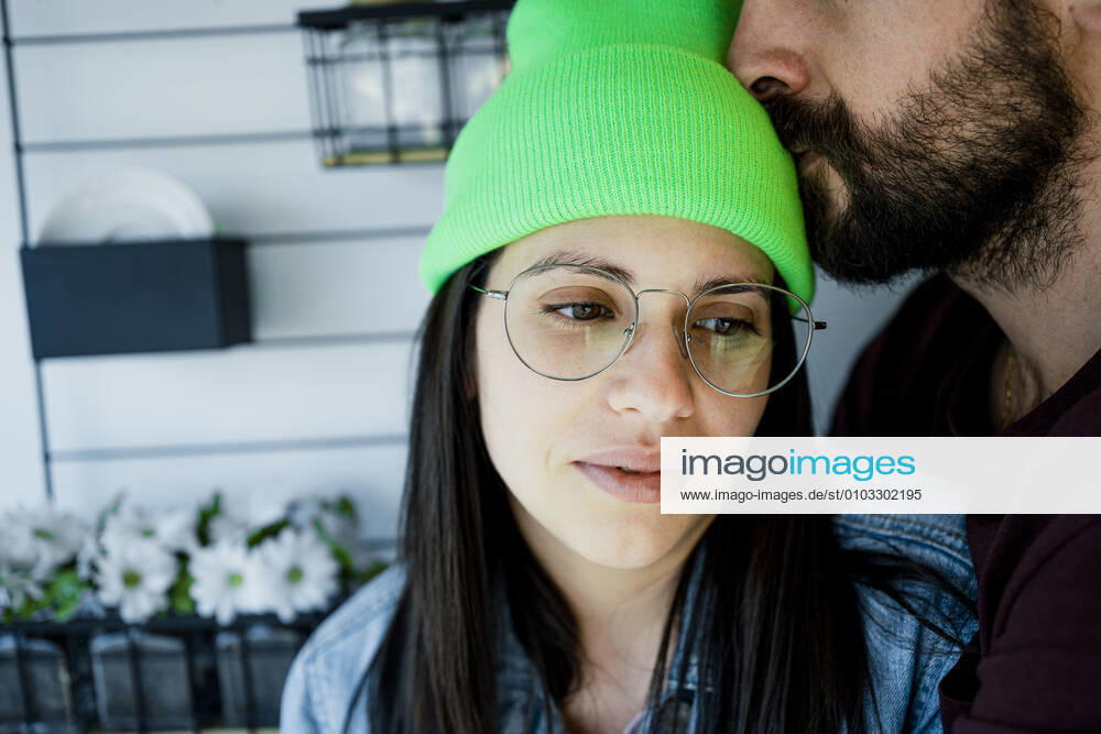Thoughtful woman being kissed by man on forehead at home model released Symbolfoto property released RCPF00273