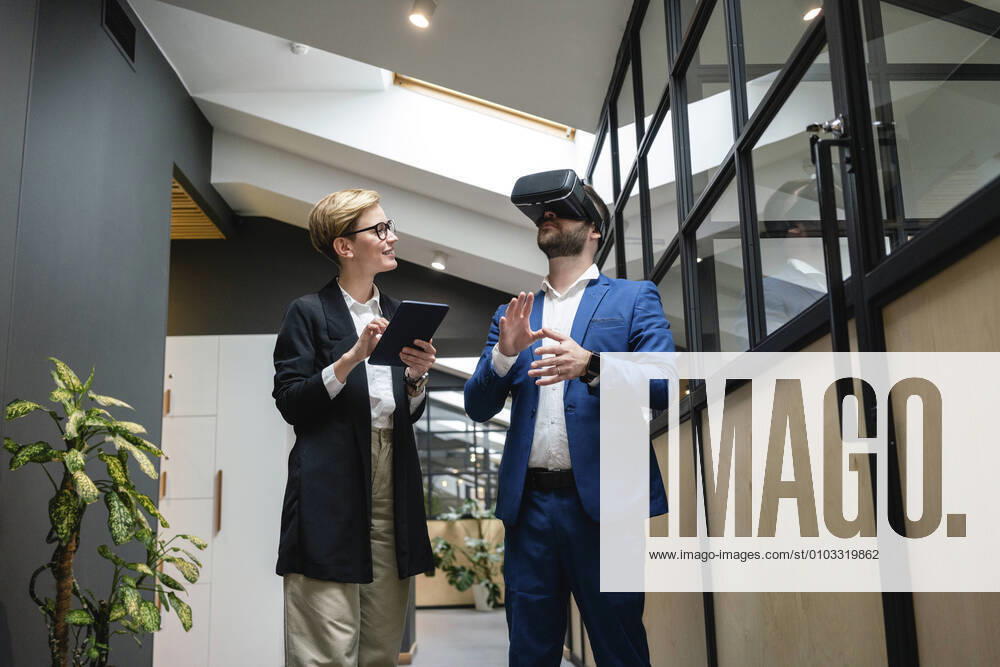 IMAGO Creative: 2022 Aussichten Businesswoman analyzing colleague using virtual simulation headset in creative office corridor model released Symbolfoto property released VPIF02662