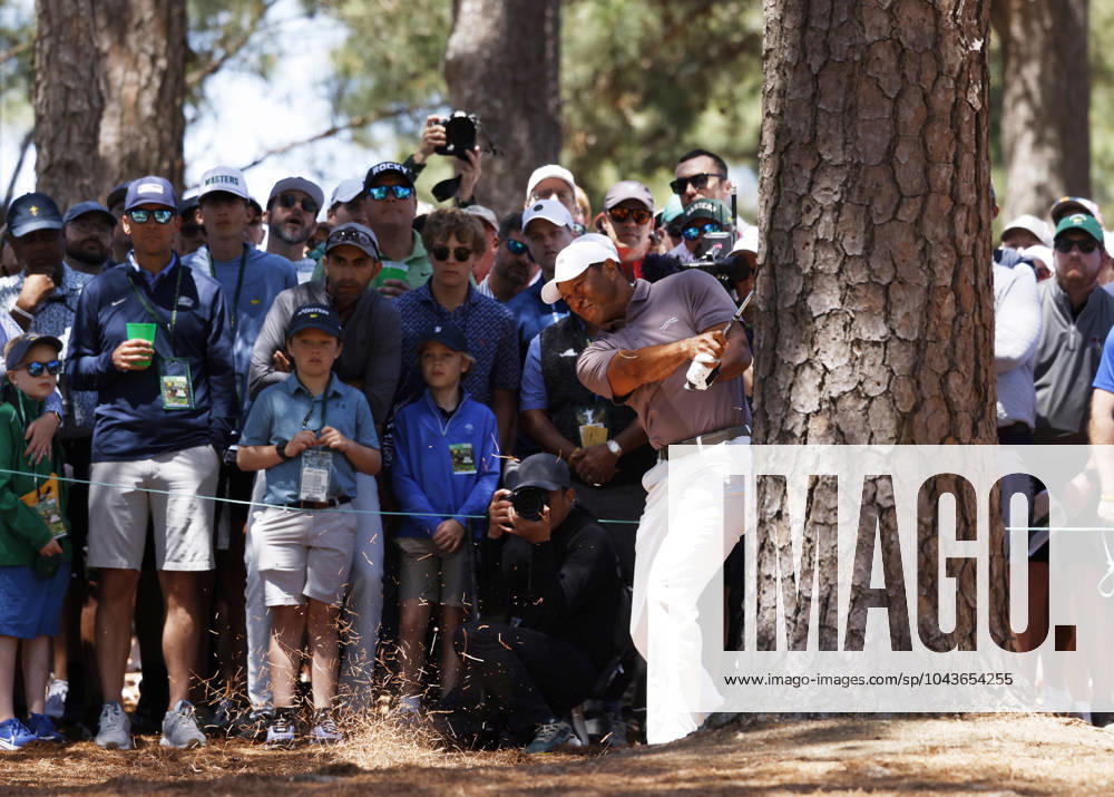 Patrons watch Tiger Woods hit his second shot on the 9th hole from behind a tree during the second round of the Masters Tournament at Augusta National Golf Club in Augusta, Georgia on Friday, April 12, 2024. Woods finished the day at one-over-par. AUG202404121001 JOHNxANGELILLO