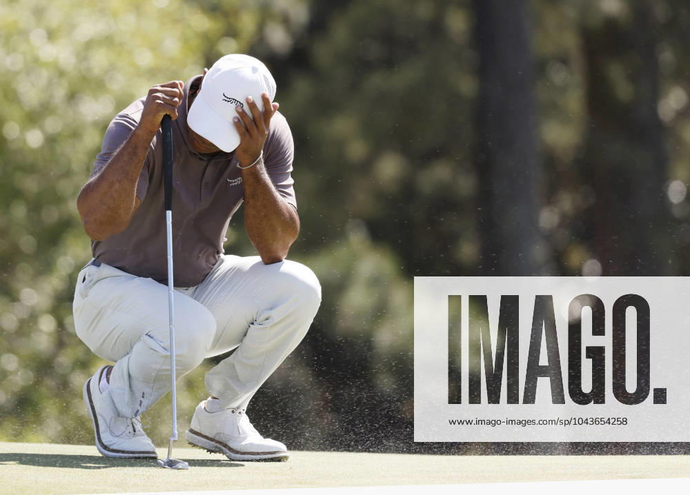 Tiger Woods covers his face as gusting wind blows sand from the bunker across the eighteenth green during the second round of the Masters Tournament at Augusta National Golf Club in Augusta, Georgia on Friday, April 12, 2024. Woods finished the day at one-over-par. AUG202404121006 JOHNxANGELILLO