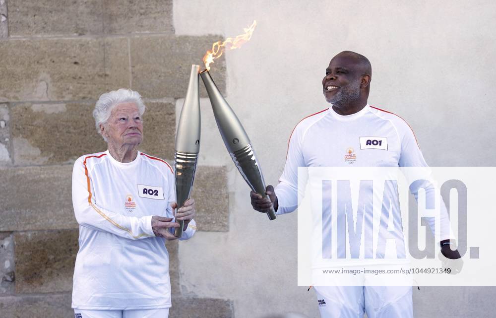 Paris Olympic torch relay begins Colette Cataldo (L) receives the Olympic flame from former French football player Basile Boli in Marseille on May 9, 2024, as the Paris Olympic torch relay begins following the arrival of the flame in the southern French port city on a majestic three-mast ship. About 10,000 torchbearers are to pass through over 400 towns until the games opening ceremony in Paris on July 26. A14AA0002809100P