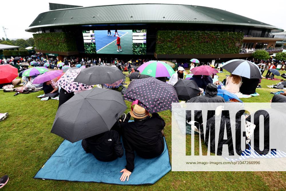 Spectators shelter under umbrellas around the grounds as rain falls before the start of play. Wimbledon Tennis Championships, Day 9, The All England Lawn Tennis and Croquet Club, London, UK - 09 Jul 2024