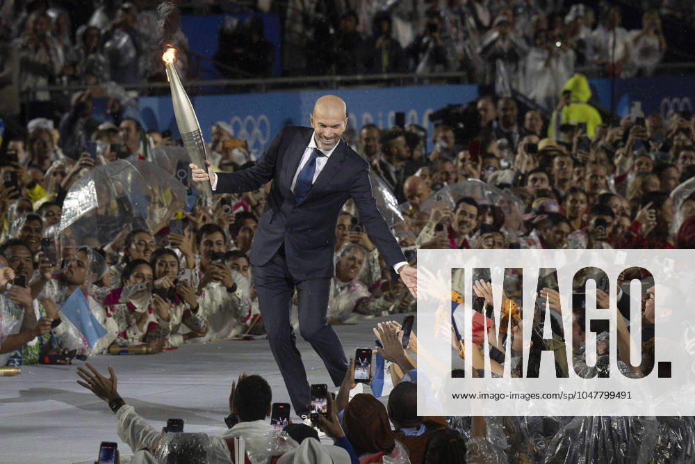 Soccer great ZINEDINE ZIDANE carries the torch at the Paris 2024 Olympics opening ceremony in the rain on July 26, 2024. Paris France - ZUMAh234 20240726_oly_h234_004