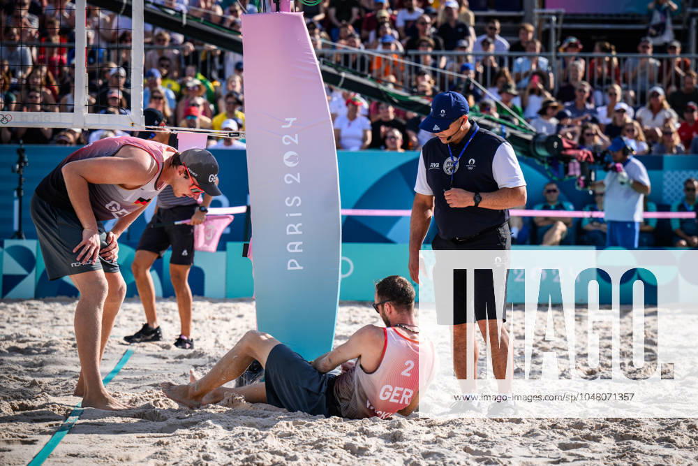 Paris, Eiffel Tower Stadium Beach volleyball, Olympic Games, preliminary round Clemens Wickler GER trips over net camera and injures himself Nils Ehlers GER and referee Giovanni Bake RSA with him