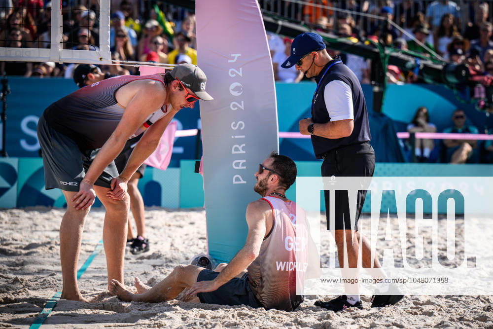 Paris, Eiffel Tower Stadium Beach volleyball, Olympic Games, preliminary round Clemens Wickler GER trips over net camera and injures himself Nils Ehlers GER and referee Giovanni Bake RSA with him