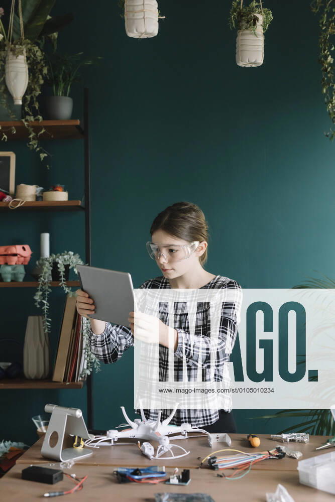 Girl using digital tablet while making quadcopter on table at home model released Symbolfoto property released ALBF01525