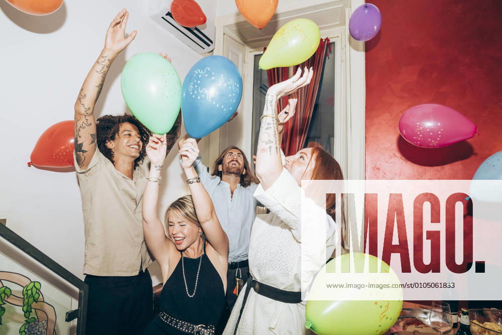 IMAGO Creative: Guten Rutsch Happy carefree friends dancing with balloons during party at home model released Symbolfoto property released MEUF01999