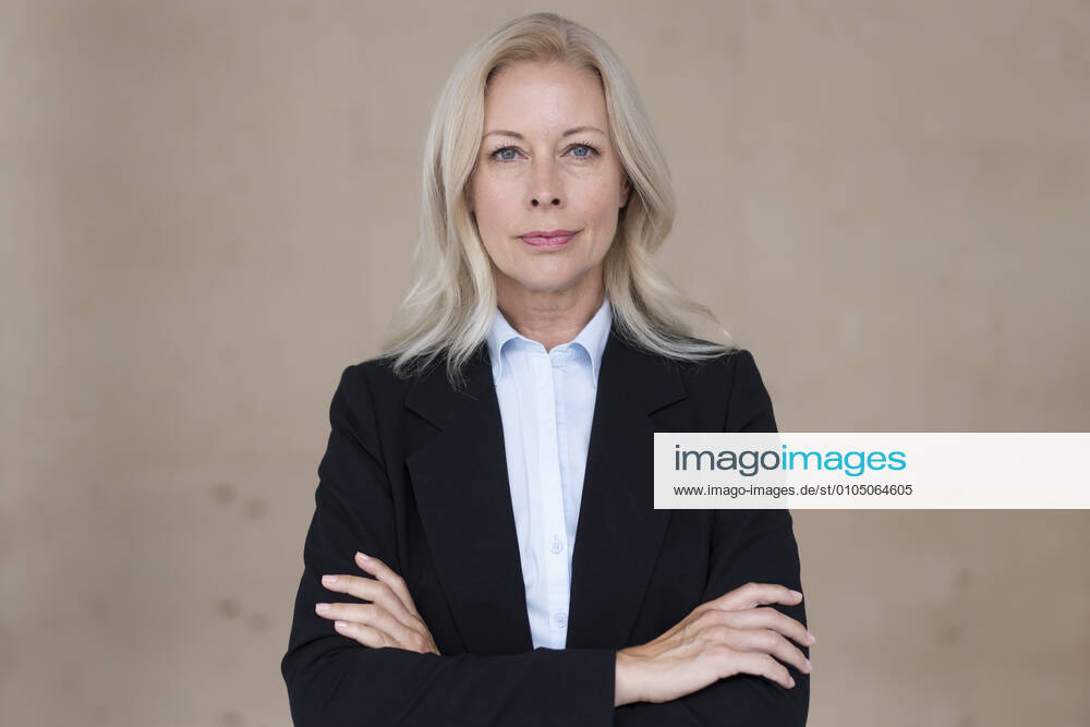 Confident female entrepreneur with arms crossed standing against wall in office model released Symbolfoto property released MOEF03232