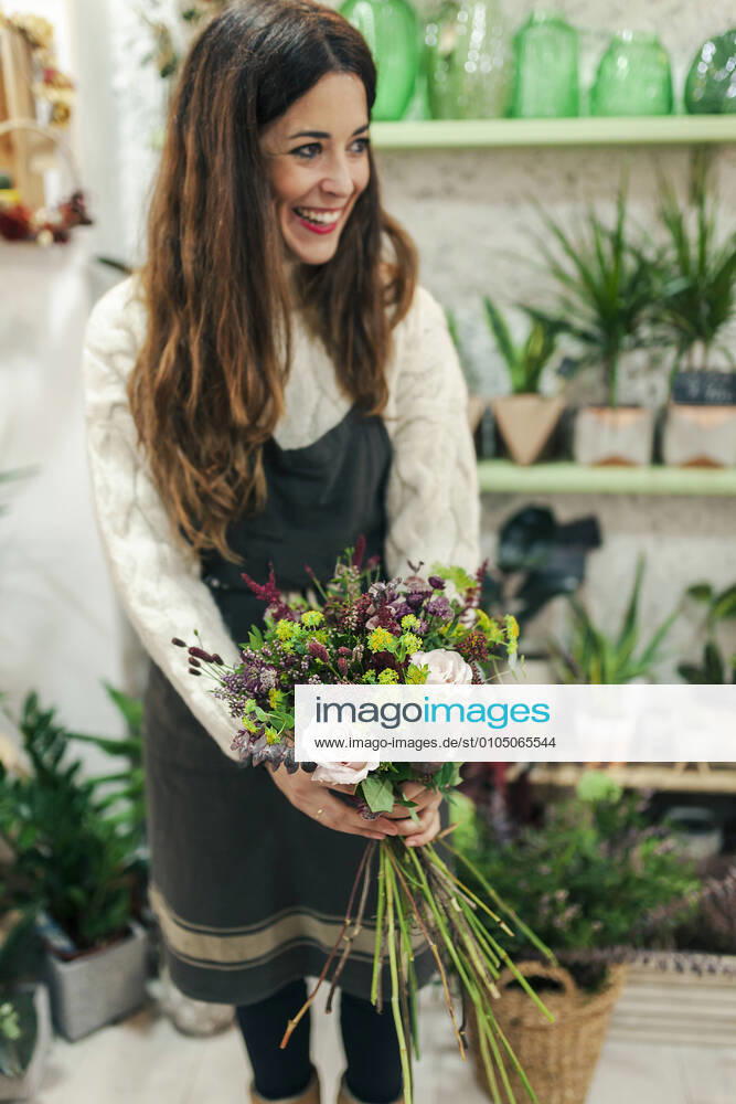 Smiling woman holding bunch of flowers while standing at flower shop model released Symbolfoto property released MRRF00400