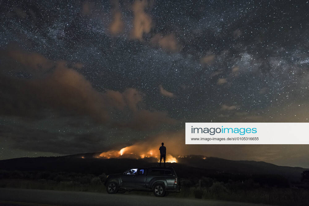 Man looking at wildfire while standing on off-road vehicle against star field Basalt, CO, United States CR_BRHU200930-501991-01 ,model released, Symbolfoto