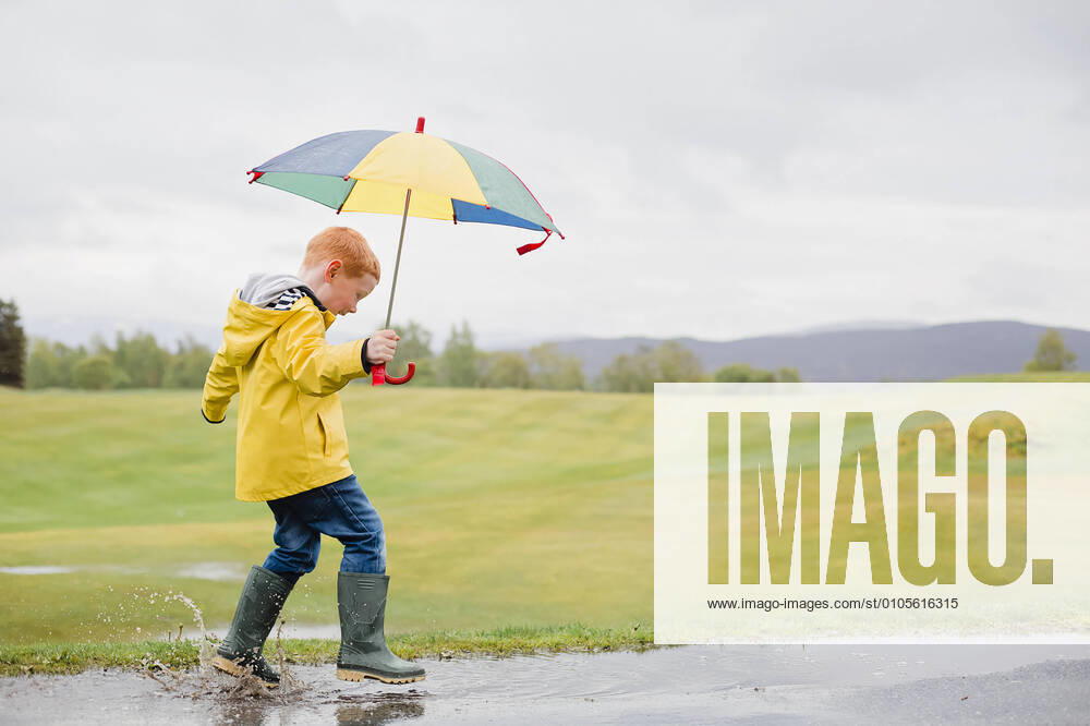 Redheaded little boy with umbrella playing in the rain model released Symbolfoto NMS00298
