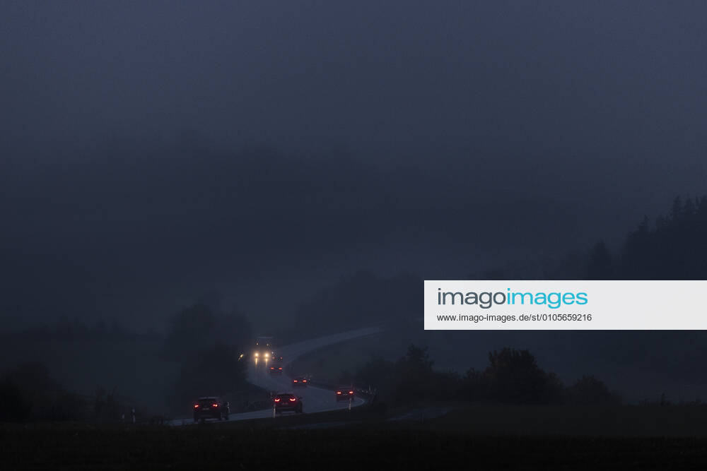 Cars drive on a country road in fog and in blue hours early in the morning near Naila, 15 10 2020 Naila Germany