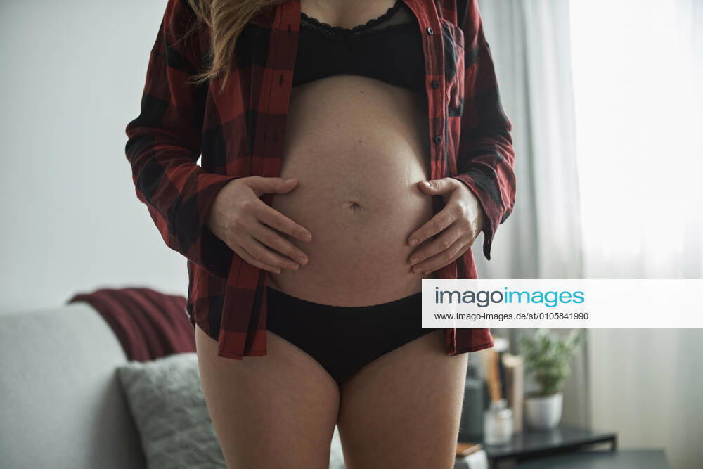 Close-up of pregnant woman with hands on stomach standing at home model released Symbolfoto property released BZF00574