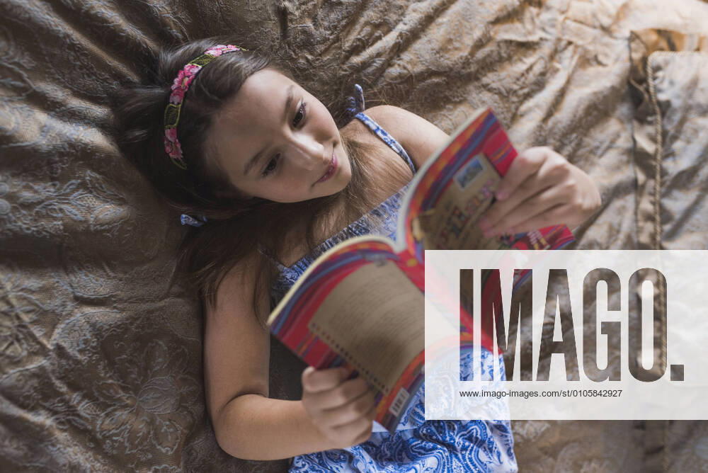 IMAGO Creative: Digitale Welt, Verzicht auf Technologie Smiling girl reading book while lying on bed at home model released Symbolfoto DSIF00137