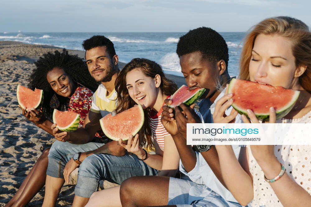 Friends eating slice of watermelon while sitting on beach during sunny day model released Symbolfoto property released RDGF00167