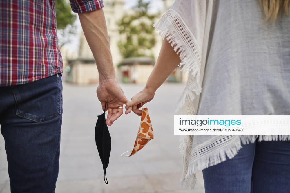 Close-up of couple with face mask holding hand on street in city model released Symbolfoto SASF00107