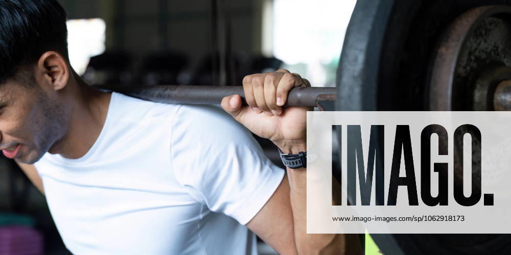 Wellness und Fitness. Nahaufnahme eines jungen Mannes, der in einem Fitnessstudio Gewichte hebt. A focused individual demonstrates strength and determination while lifting weights in a fitness environment. (License=RF) 23462725 ,model released, Symbolfoto