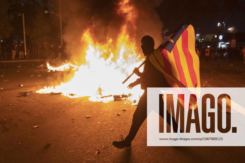 FC Barcelona, Barca v Real Madrid: La Liga BARCELONA, SPAIN - DECEMBER 18: A protester carries a Catalan pro-independence Estelada flag stands next to a burning barricade during a protest called by Catalan separatist movement Democratic Tsunami outside the Camp Nou stadium in Barcelona on December 18, 2019, during the El Clasico Spanish League football match between Barcelona FC and Real Madrid CF. Catalonia Spain. Editorial use only. Please get in touch for any other usage.