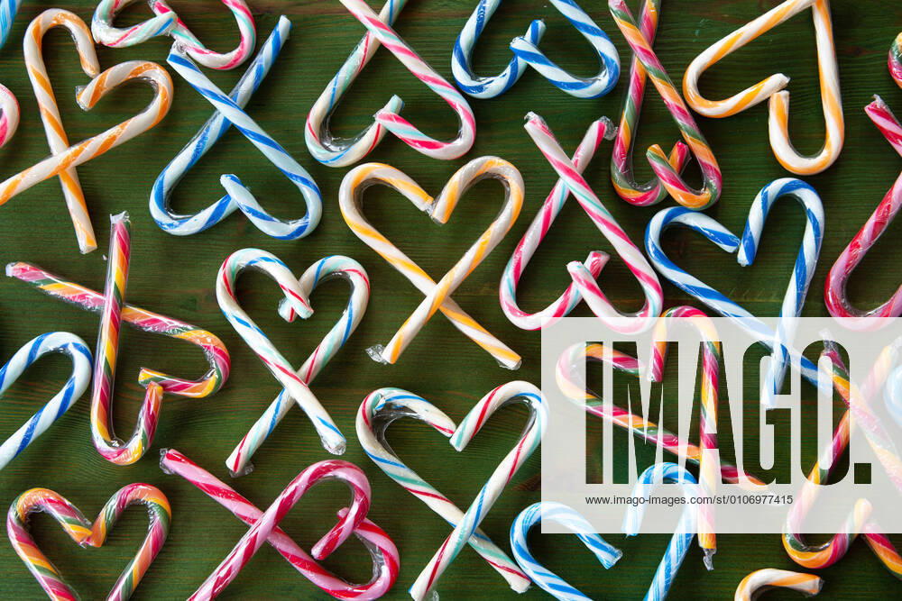 Colorful candy canes in hearts arranged on a green background 1079706386