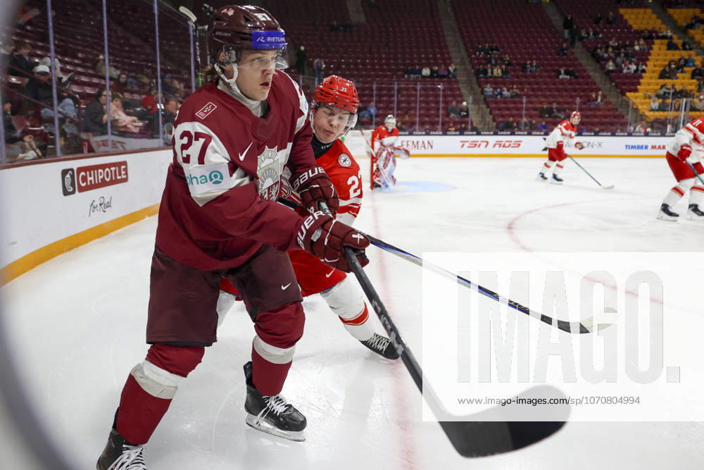 Latvia forward MARKUSS SIERADZKIS (27) and Denmark forward LASSE BAERENTSEN (23) connect in the corner. Latvia and Denmark faced off in the opening round of the IIHF World Junior Championship on December 30th. Latvia was victorious winning 6-3. Minneapolis United States - ZUMAt166 20251230_zsp_t166_021