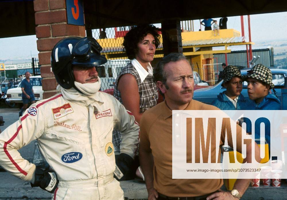 The reigning World Champion Graham Hill (GBR) watches an event further up the pit lane with the Lotus Team Manager Colin Chapman (GBR) and his faithful timekeeper, wife Bette...South African Grand Prix, Kyalami, 1 March 1969. ....BEST IMAGE