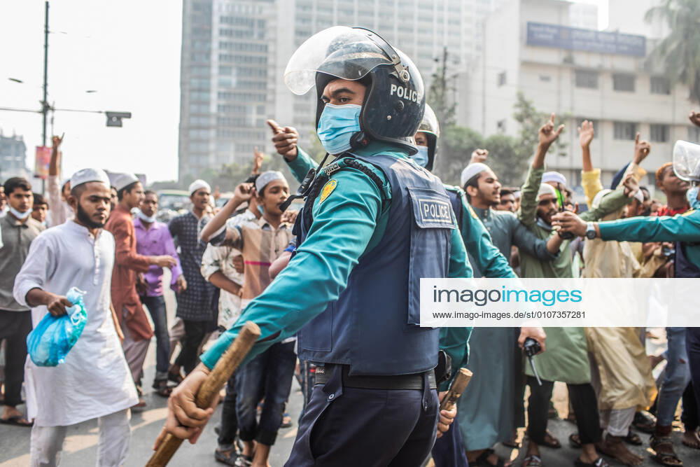 Policemen look on as protesters march along the Streets during the demonstration..Police have dispersed a rally, organized by Qawmi madrasa students to protest against construction of sculpture, started from the South gate of Baitul Mukarram National Mosque after Jumma prayer on Friday. Dhaka Bangladesh - ZUMAs197 20201204_zaa_s197_030