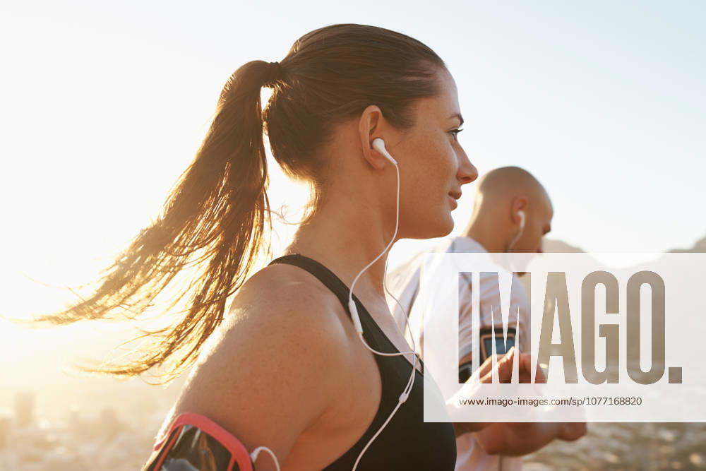 Getting into the running mood with some awesome tunes. a young couple exercising outdoors (License=RF) 20218723 ,model released, Symbolfoto