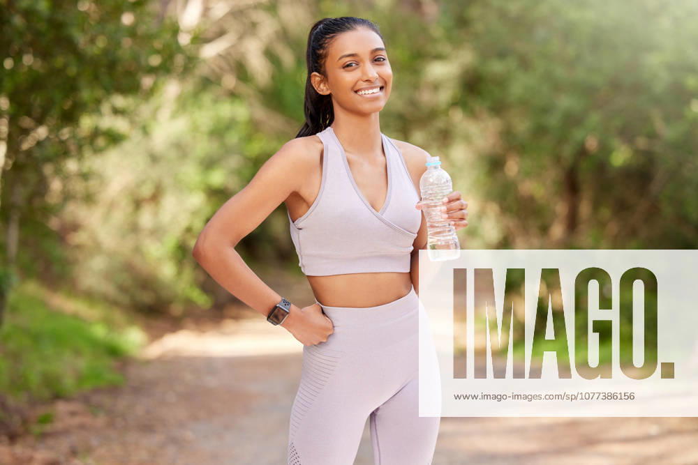 Woman, bottle and outdoor in portrait with smile for exercise, workout or running in the forest. Happy, female person or athlete in nature for fitness, training and health with water drink to relax. (License=RF) 21870626 ,model released, Symbolfoto