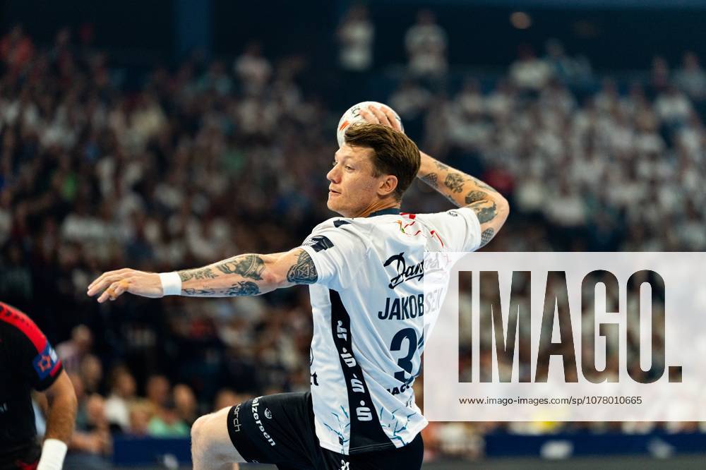 Emil Jakobsen 31 SG Flensburg Handewitt takes a shot with the ball in his raised throwing hand and jumps in the process A well-filled grandstand can be seen in the background MT Melsungen vs SG Flensburg Handewitt - EHF Finals Hamburg 2026
